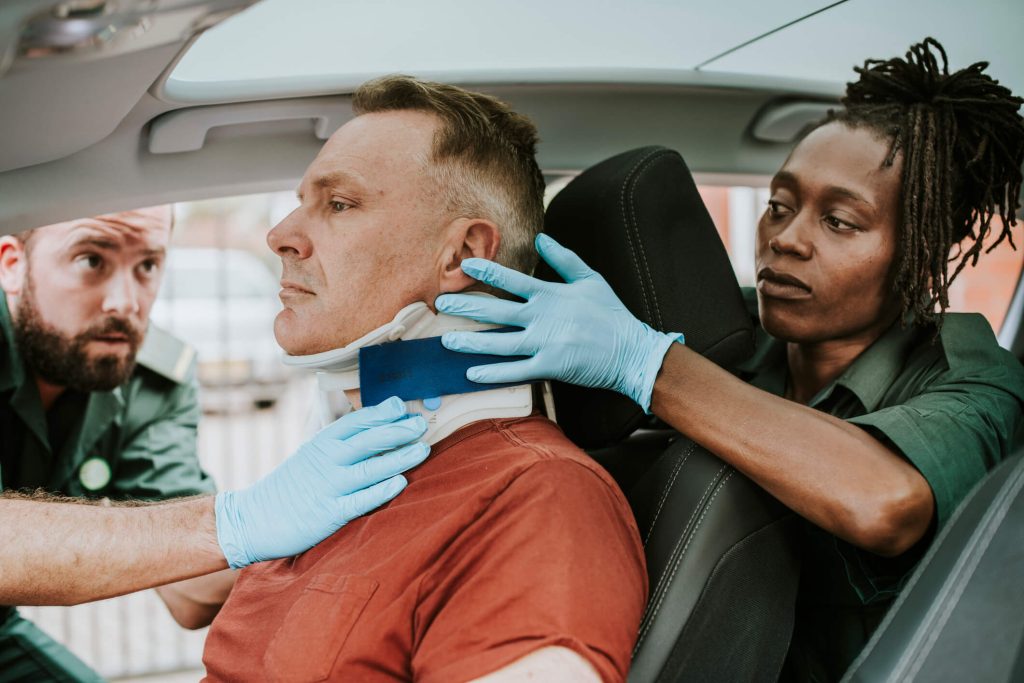 Paramedic placing a cervical collar on an injured man after a car accident