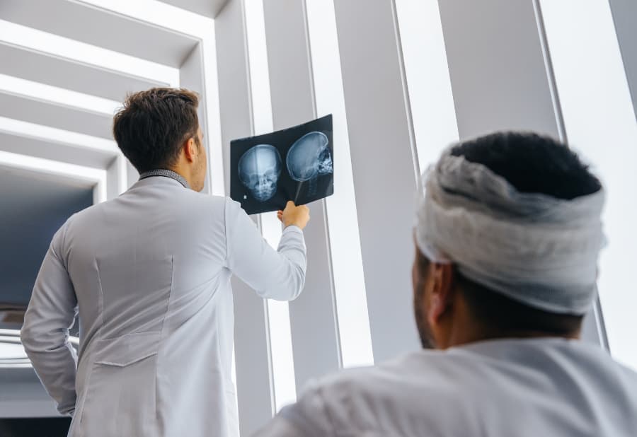 Doctor holding up a head x-ray, showing it to a patient in a wheelchair.
