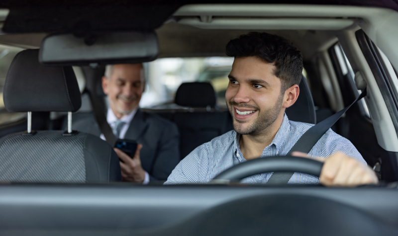 Close-up of a rideshare driver talking with a man in the back seat