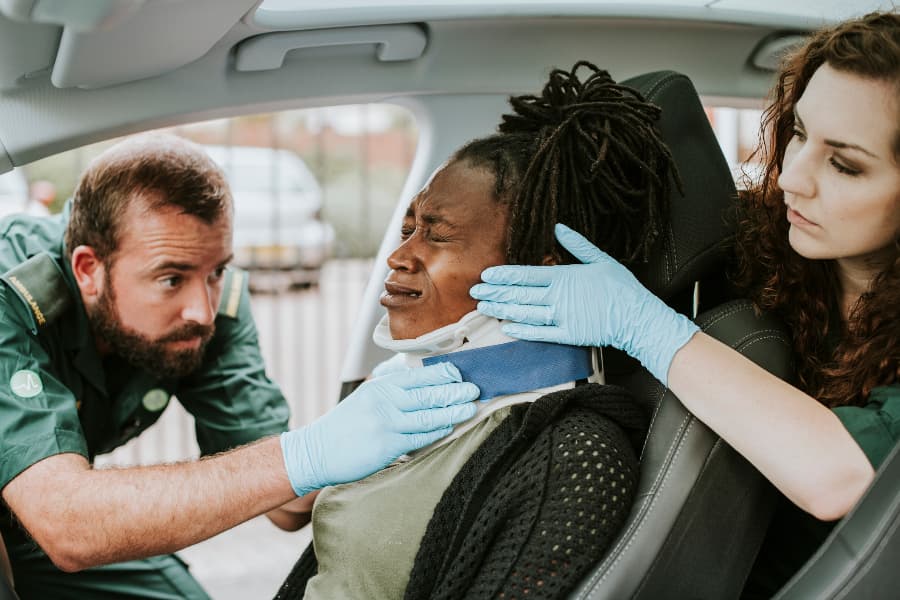 Paramedics placing a cervical collar on a woman who’s suffered car accident injuries.