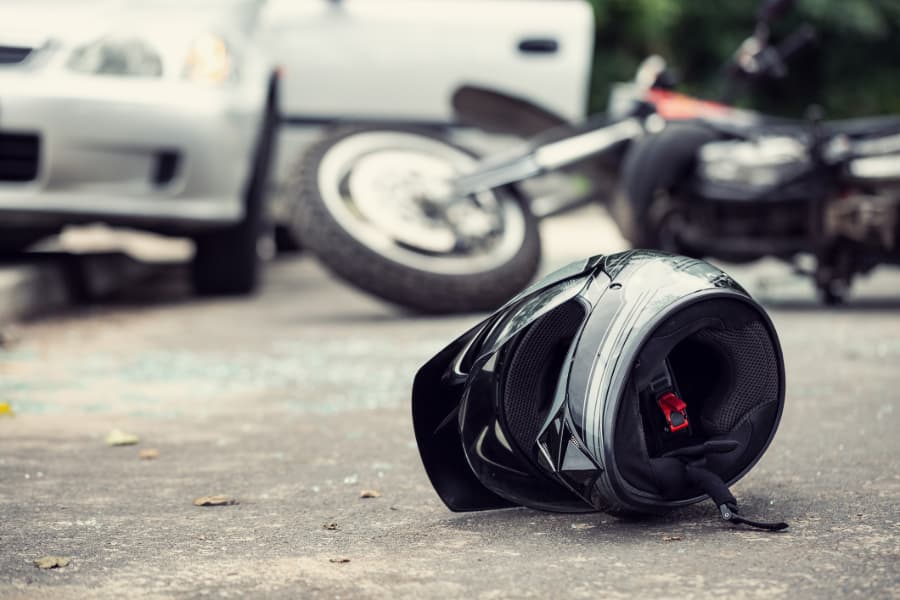 Close-up of a helmet on the road with a blurred motorcycle and car in the background